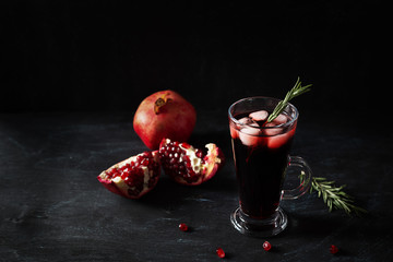 Pomegranate Christmas cocktail with rosemary, champagne, club soda on black table. Xmas drink.