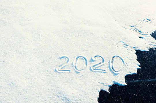 Inscription of new year 2020 on the snow surface on ice. Winter holiday background