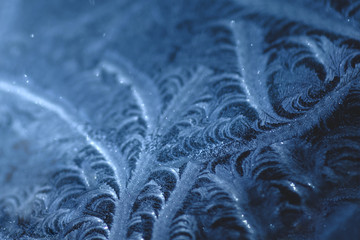 Frosty pattern on car glass in blue tones.
