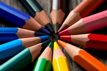 group of colored pencils lie in a circle on a wooden table - Powered by Adobe