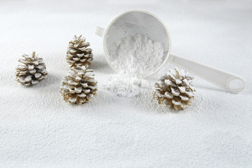 Fototapeta na wymiar Christmas decoration cones covered snow made of icing sugar with sieve. Christmas forest concept. Golden colored pine cones covered sugar powder and sieve..