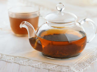 Glass teapot and cup full of fresh black tea