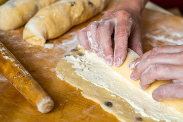 Woman preparing a roll of yeast dough with curd filling