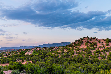 Fototapeta na wymiar Sunset pink twilight in Santa Fe, New Mexico mountains Tesuque community neighborhood with houses green plants pignon trees shrubs and blue sky clouds