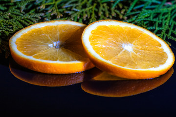 Two slices of orange close-up, black mirror background,