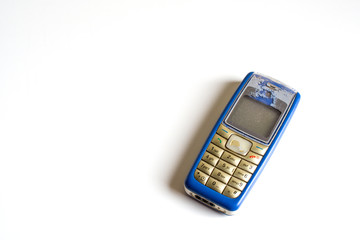Old mobile phone on a white desk. top view, copy space.