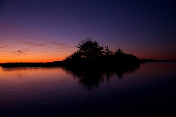 Obraz na płótnie Canvas Sunset over Assateague Island over marshes, salt water bay with silhouette