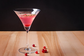 Red color cocktail with cranberry in martini glass on the wooden table
