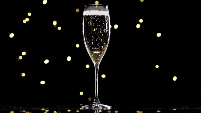 champagne in a glass, concept of new year and Christmas champagne pouring in a glass dark background with beautiful yellowbokeh. champagne pour into a glass. Close up shot. Slow motion