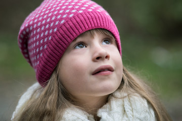 Pretty child girl in warm knitted winter clothes outdoors.