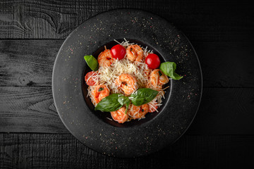 Spaghetti salad or pasta with shrimp, cherry tomatoes, cheddar cheese, parmesan, basil and sauce. Nutritious, dietary, fitness food. Black boards background