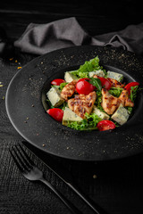 Salad of iceberg lettuce, lettuce, cherry tomatoes, grilled chicken and dorblu cheese. Nutritious, dietary, fitness food. Black boards background