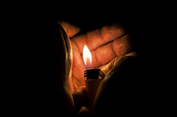 A photo with a mysterious feel to it showing the hands of a man with a lighter and it's flame