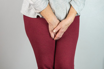 senior woman with hands between legs isolated on White background