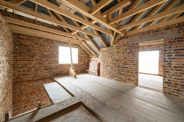 Interior of unfinished brick house with concrete floor, bare walls ready for plastering and wooden...
