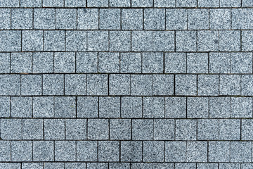 Texture of gray square road granite tiles. Stone background. Modern paving slabs. Motley pattern.