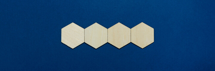Wide view image of four blank wooden hexagons placed in a line. Over classic blue background with...