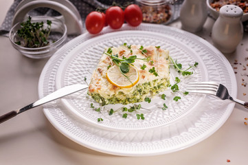 Close-up vegetarian lasagna with spinach and microgreens on a white plate. Tasty and healthy mediterranean food.