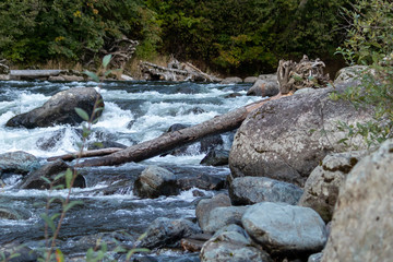 large boulders sticking out of rapids on a blue river