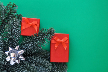 Christmas mood colors: red gifts, fir branches and green background.