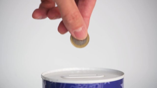 Male hand putting a coin in 50 cent and 1 Euro into tin can saving bank on white background. Close-up.