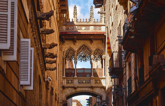 Barri Gotic Quarter in Barcelona, Spain. Antique Bridge between stone walls of medieval buildings in in old town. Famous touristic landmark and travel destination. Sunset evening street perspective.