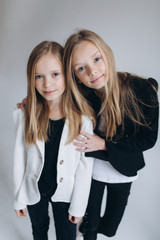 Young fashion models posing together smiling and hugging together in studio on isolated white background. Fashion, natural beauty, sisterhood concept