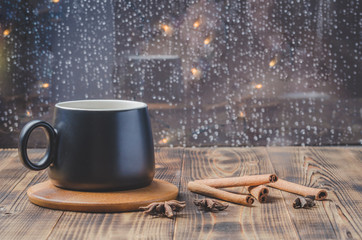 Obraz na płótnie Canvas Eggnog. Traditional christmas cocktail in a black mug on a bamboo stand with cinnamon sticks and anise on wooden table.