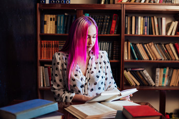 girl reading a book in the library is preparing for exams