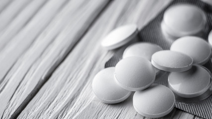white pills on white wooden background close up