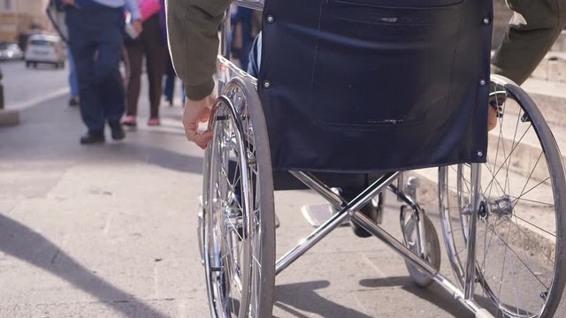 handicaps, architectural barriers. disabled man pushing wheelchair on sidewalk