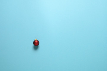 Einzelne rote Weihnachtskugel vor hellblauem Hintergrund