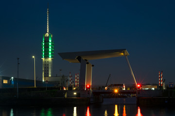 Naklejka premium Illuminated radio tower and Rijnhaven bridge along a waterside in the town of Alphen aan den Rijn, Netherlands.