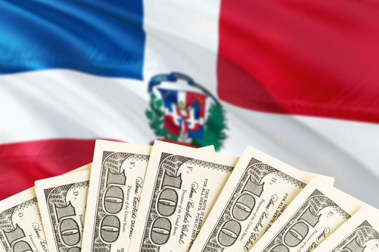 Dominican Republic economy concept. Dollar banknotes on the side of national flag with waving background. Financial theme.