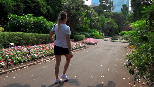 girl walks in the park along flower beds