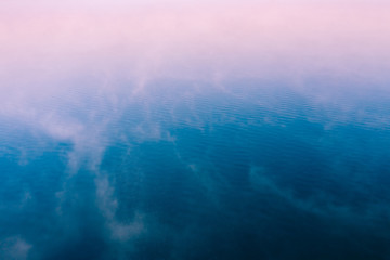 Pink fog over blue water surface, aerial view. Tranquil natural background