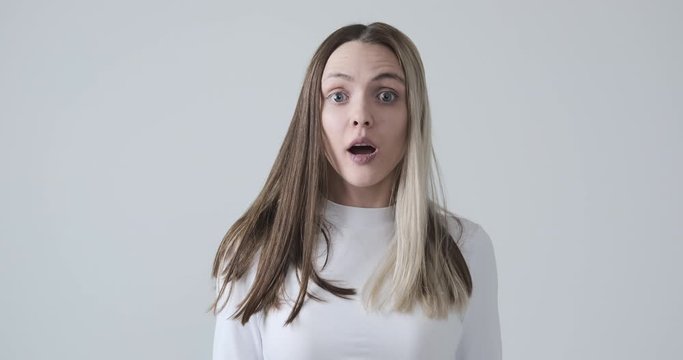 Young woman shocked while turning around over white background