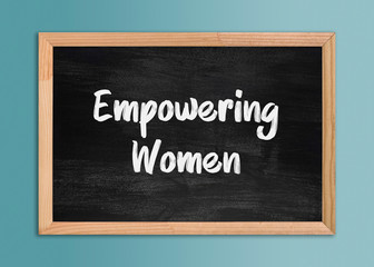 Vintage chalkboard in wooden frame on aqua menthe background. Chalkboard isolated with "Empowering Women" message