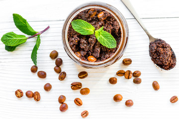 Homemade cosmetics with coffee scrub on white desk background top view