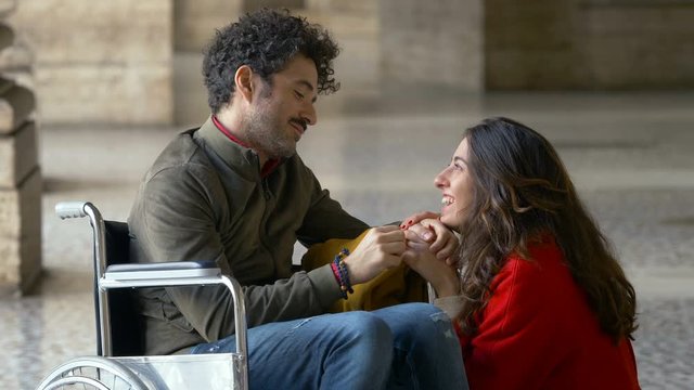  paraplegic man in the wheelchair with his girlfriend kneeling down next to him
