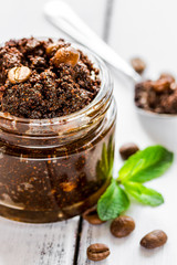 Homemade cosmetics with scrub and coffee beans on desk background
