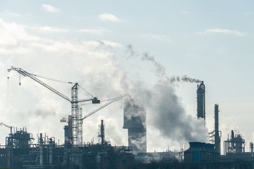 Chemical industry. Environmental pollution by harmful emissions into the atmosphere. Poisonous smoke comes from the big pipes. The factory poisons nature. Silhouette of pipes and smoke. Sunny day.