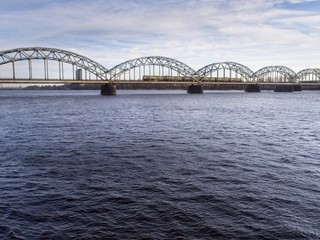 A train is crossing the Daugav River heading to Riga Central Station on a cold day in March 2018
