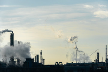 Chemical industry. Environmental pollution by harmful emissions into the atmosphere. Poisonous smoke comes from the big pipes. The factory poisons nature. Silhouette of pipes and smoke. Sunny day.