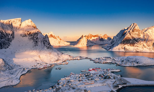 Amazing aerial view of Lofoten Islands nature from drone, winter sunrise snowy scenery of village Reine, Sakrisoy and Hamnoy during beautiful mountain ridge with alpenglow, scene over polar circle.