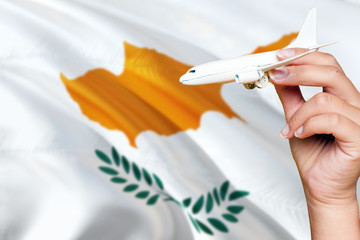 Cyprus travel concept. Woman holding a miniature plane on national flag background. Holiday and voyage theme with copy space for text.