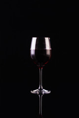 Glass of red wine on black background. Aromatic wine. Strict style. Wine on the dark