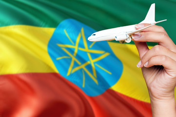 Ethiopia travel concept. Woman holding a miniature plane on national flag background. Holiday and voyage theme with copy space for text. © sezerozger