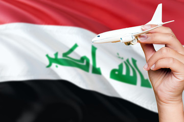 Iraq travel concept. Woman holding a miniature plane on national flag background. Holiday and...