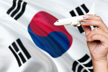 South Korea travel concept. Woman holding a miniature plane on national flag background. Holiday and voyage theme with copy space for text.